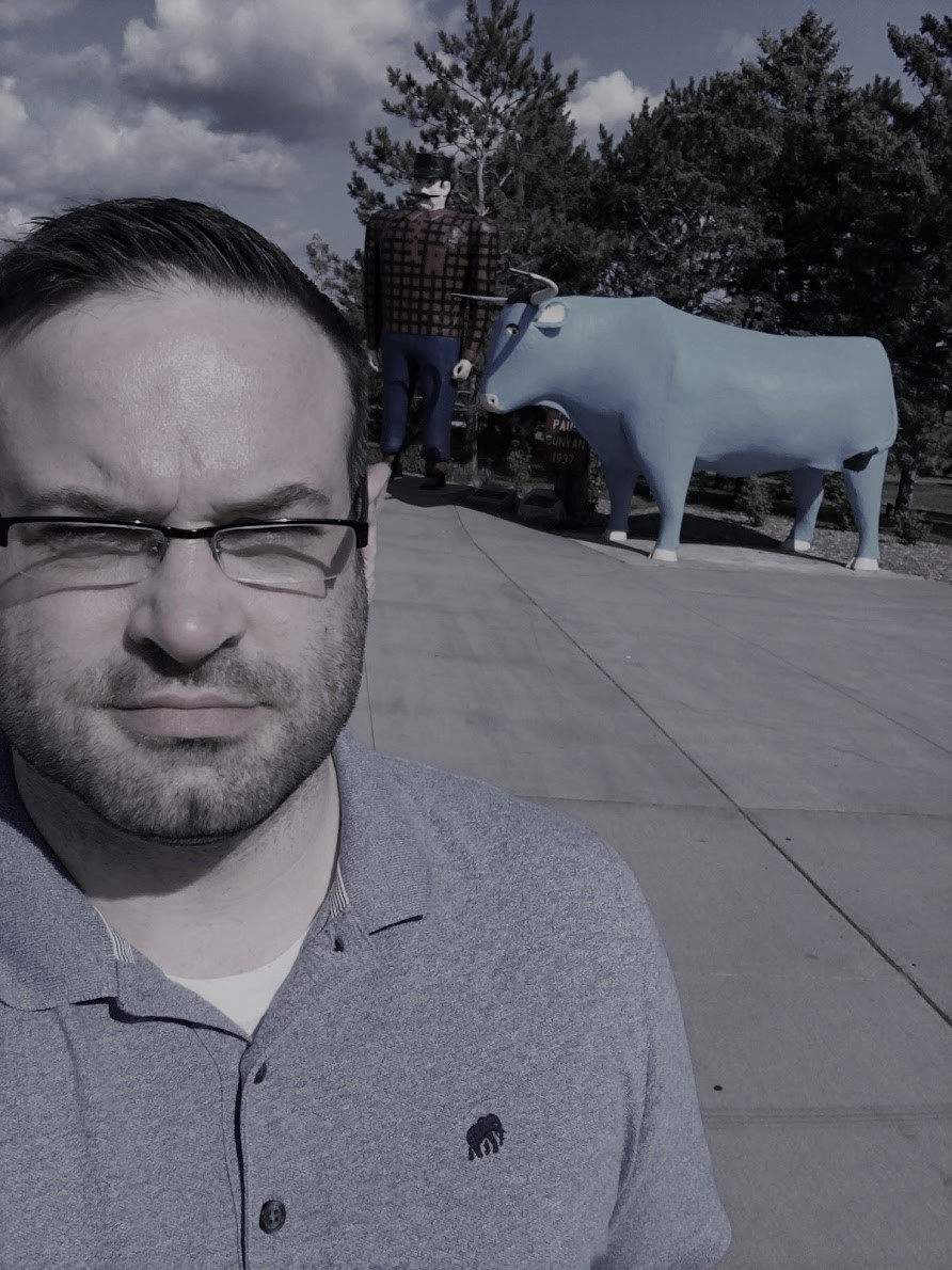 Rob Stewart in front of Paul Bunyan and Babe the Blue Ox statues