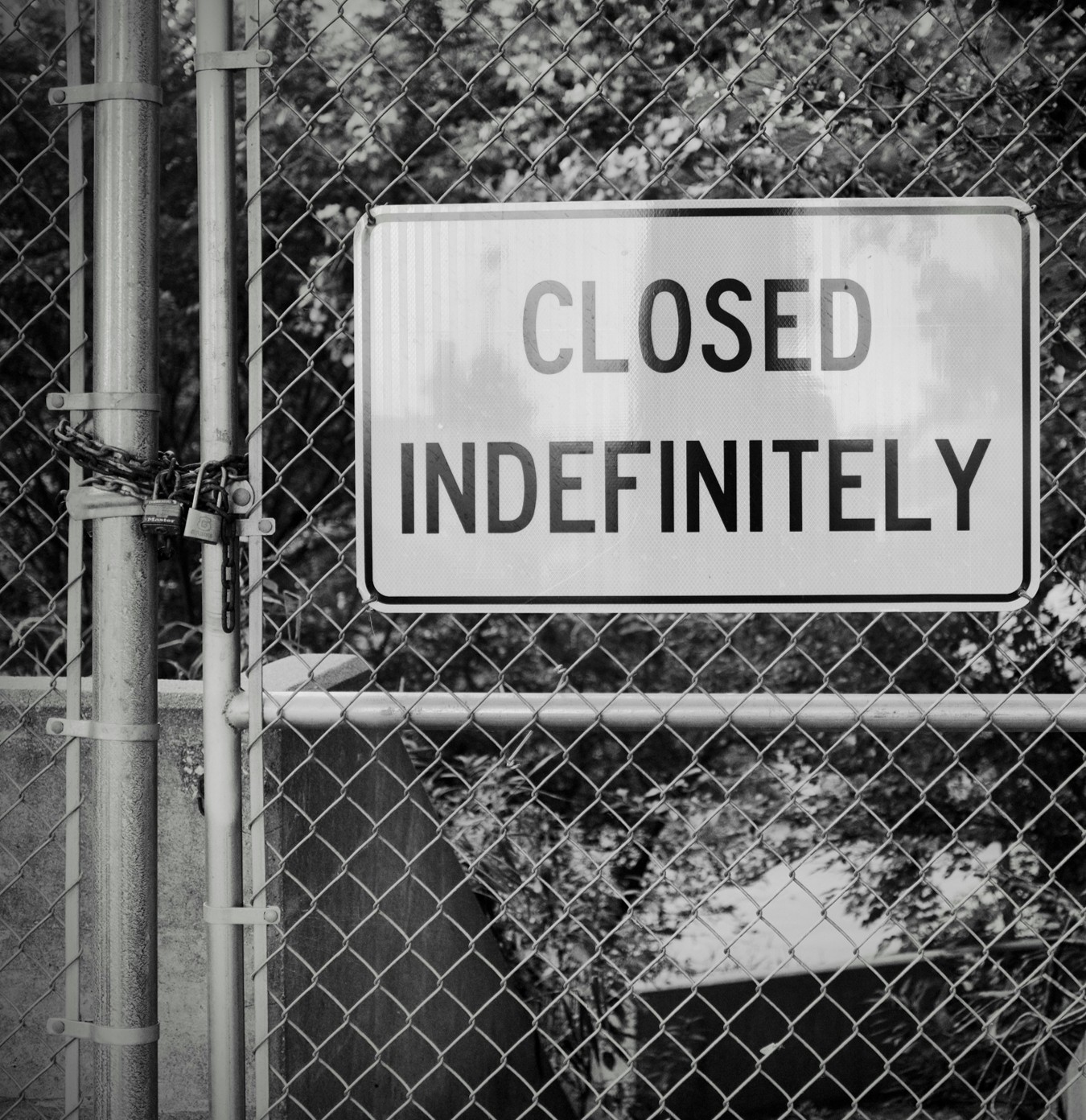 Locked chain-link gate with a sign reading Closed Indefinitely